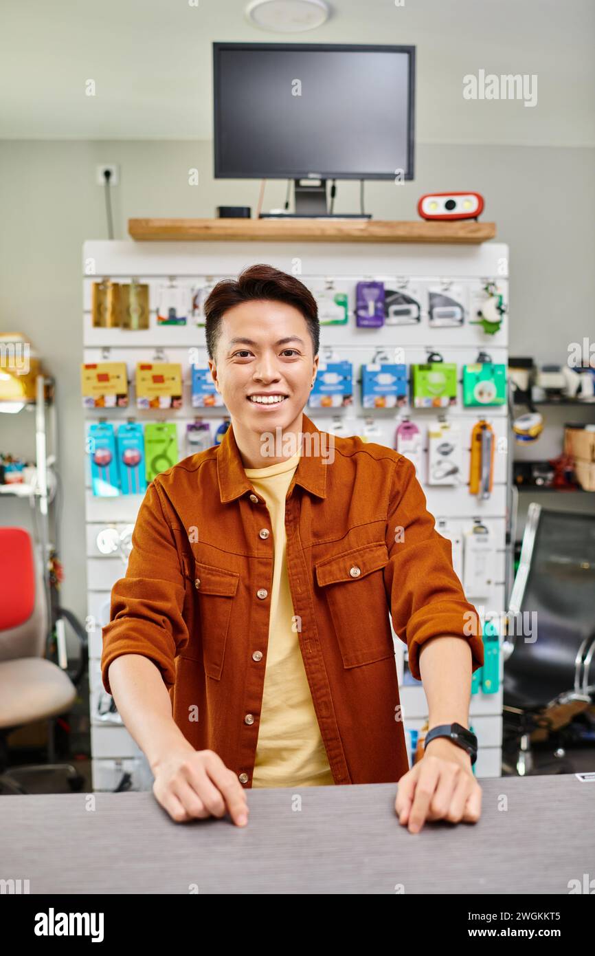 cheerful asian entrepreneur looking at camera in own electronics store, small business concept Stock Photo