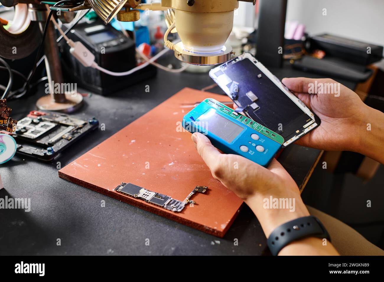 cropped view of technician working with smartphone and voltmeter in repair shop, small business Stock Photo