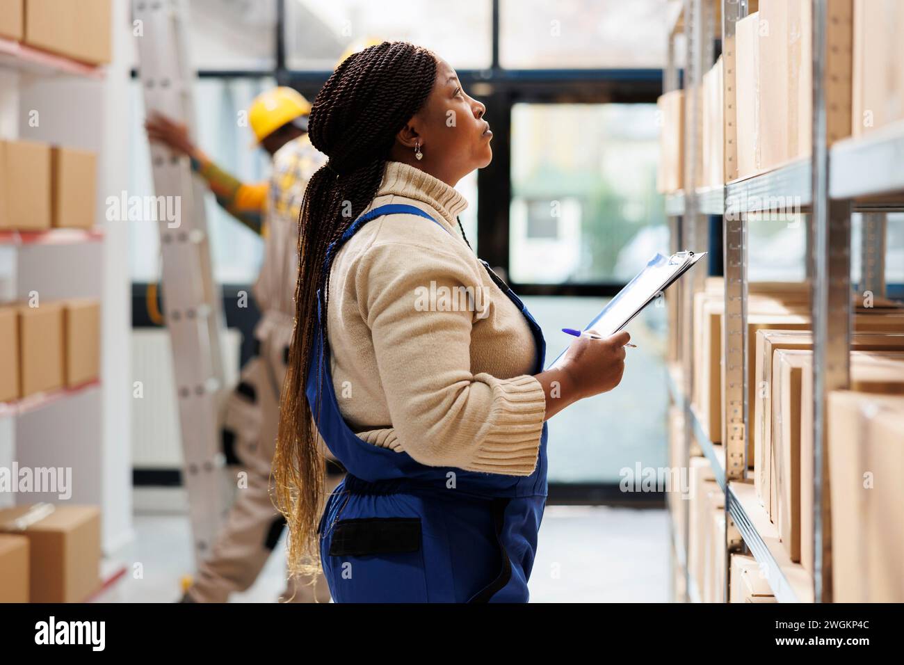 Warehouse supervisor looking at parcels and taking notes in storage ...