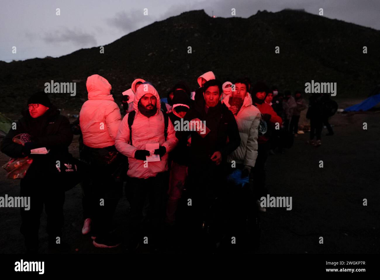 Asylum-seeking migrants hold their documents as they line up in a ...