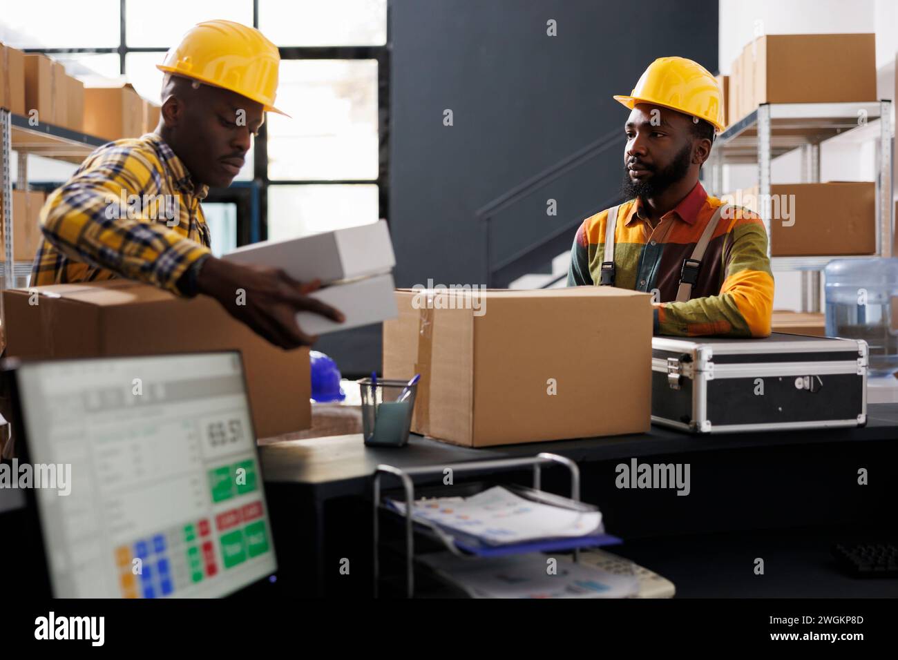 Warehouse employees putting packed boxes on counter desk ready for shipment. African american e commerce retail storehouse managers preparing customer packages for transportation Stock Photo