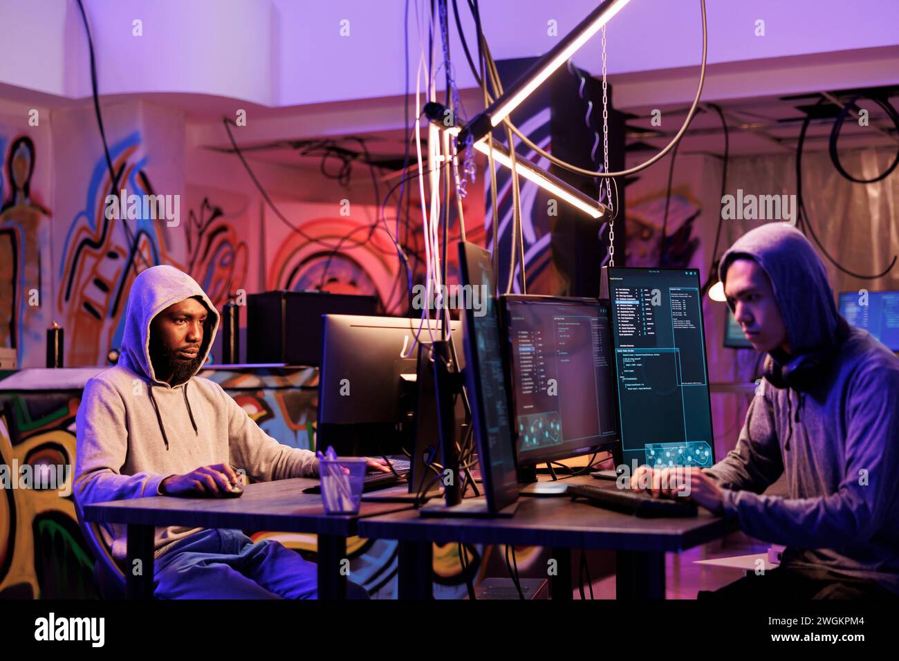 Two hackers using malware to break into system and steal information. Internet criminals coding illegal malicious software for cracking password and hacking computer network Stock Photo