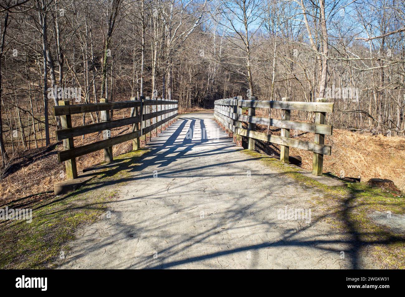 A captivating bridge guides the way with prominent lines towards the scenic footpath along the Youghiogheny River Trail at Cedar Creek Park in Westmor Stock Photo