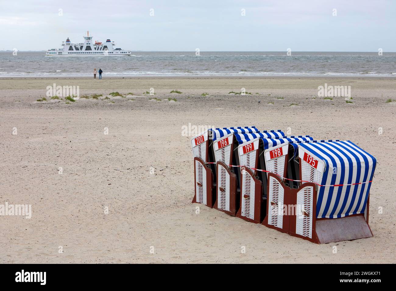 beach chairs tied together on the beach, only two people on the water with a ferry, the end of the season , Germany, Lower Saxony, Norderney Stock Photo
