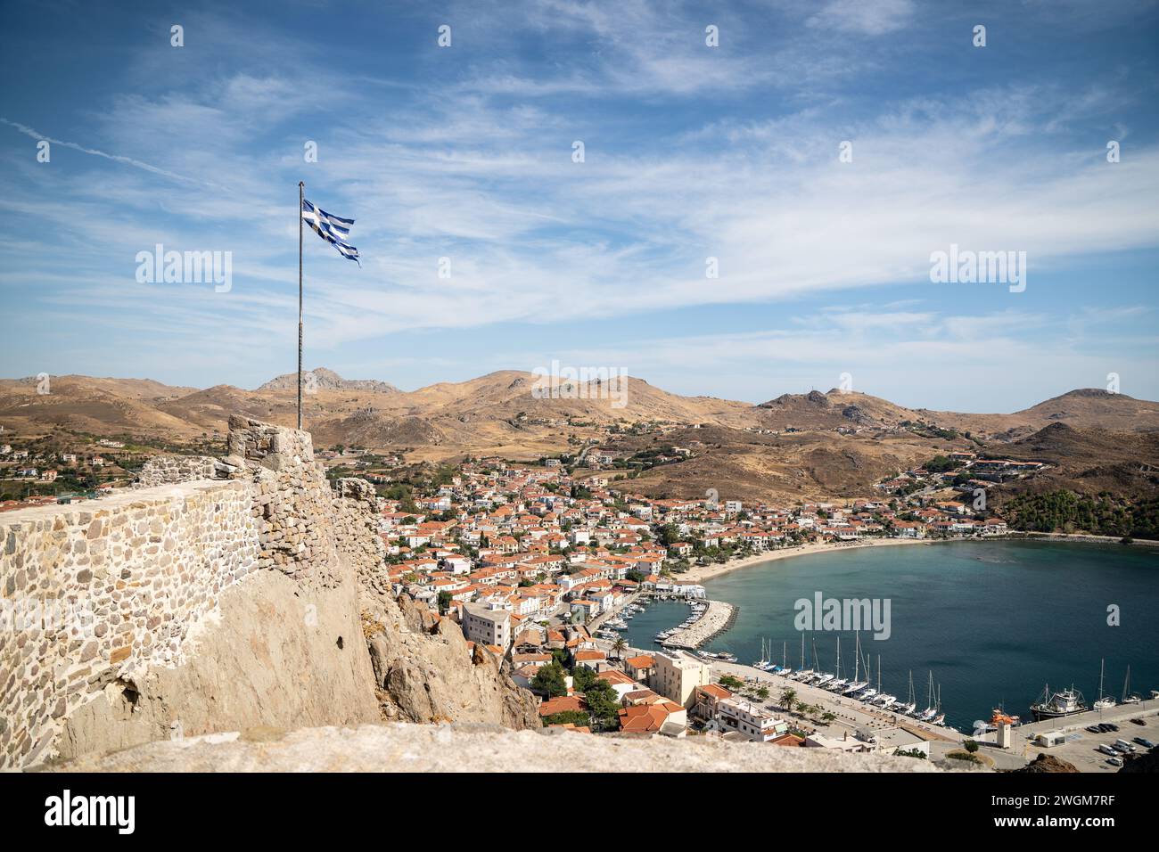 Myrina's Grandeur: A captivating view of a castle and the Greek Flag soaring high above the historic capital of Lemnos, Greece. Stock Photo
