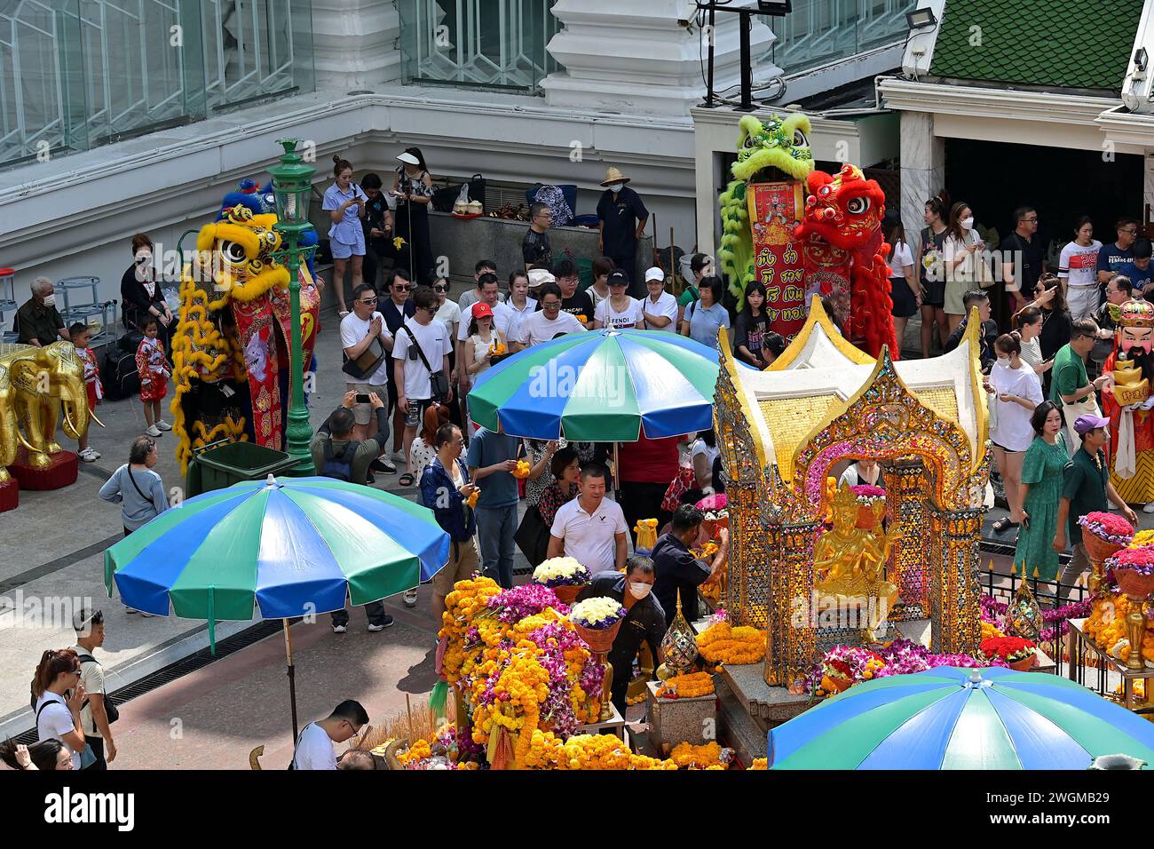 The Erawan shrine is a popular tourist destination in Bangkok & visitors come here to pray for good fortune & protection, seen with lion dance troupe Stock Photo