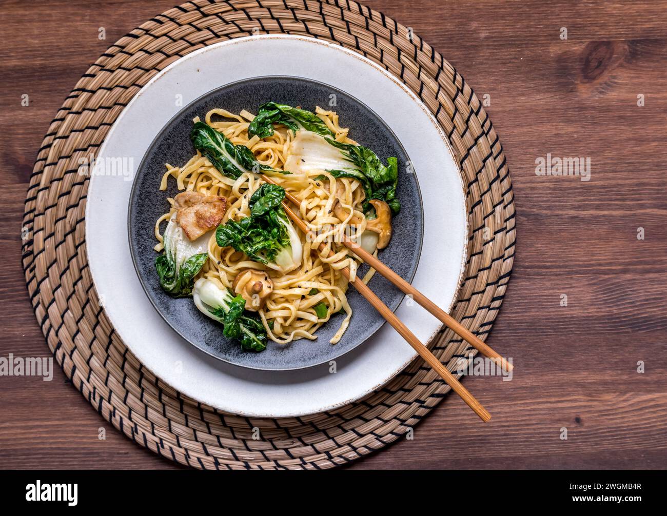 A dish of lo mein noodles with baby bok choy, cremini mushrooms and pork. Stock Photo