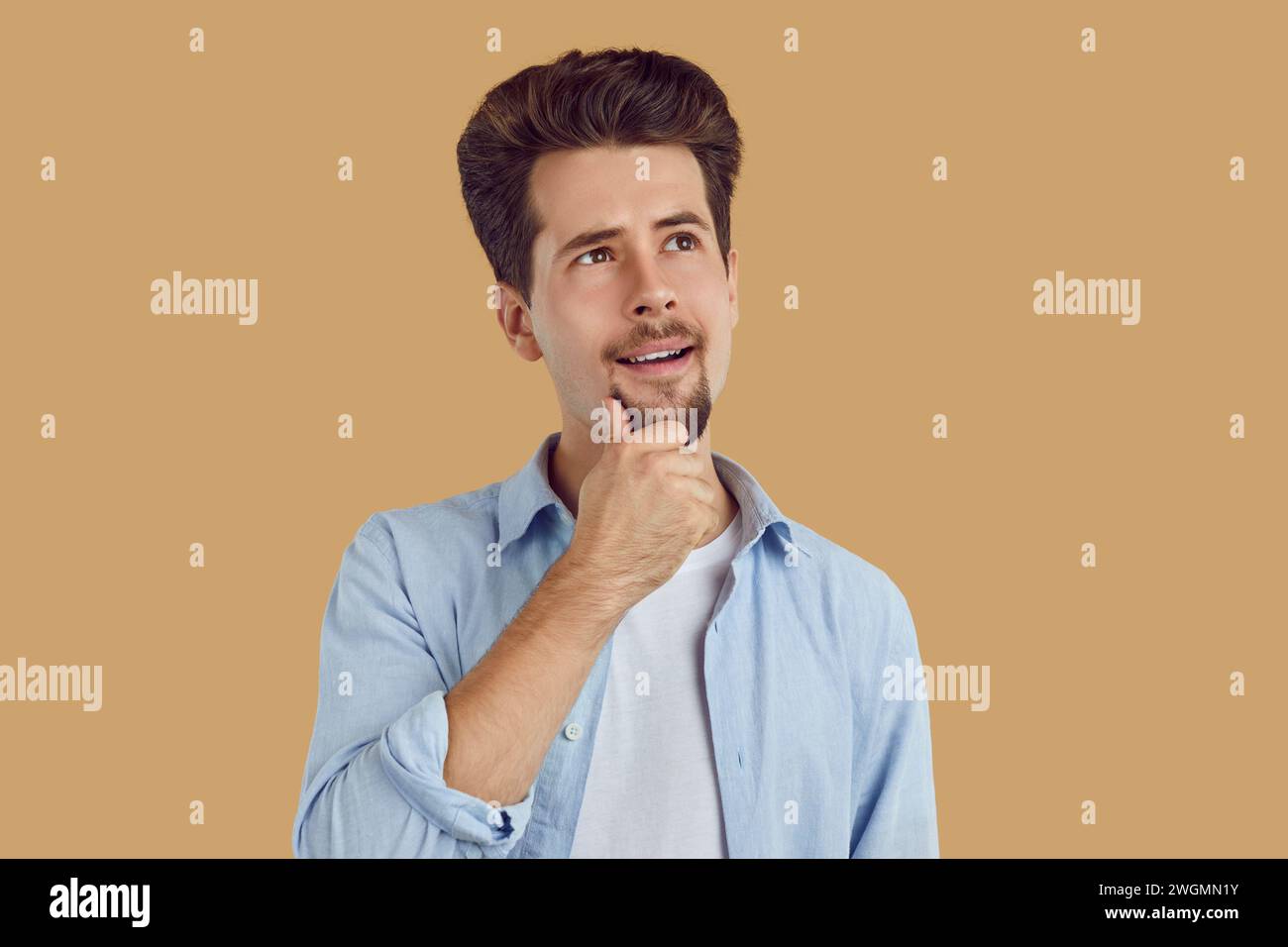 Young handsome smiling man with a doubtful thoughtful expression. Stock Photo