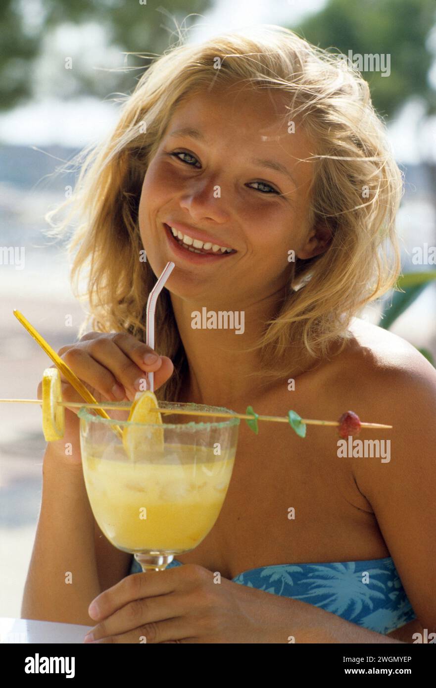 pretty Blond girl drinking coktail smiling front camera happy holidays Stock Photo