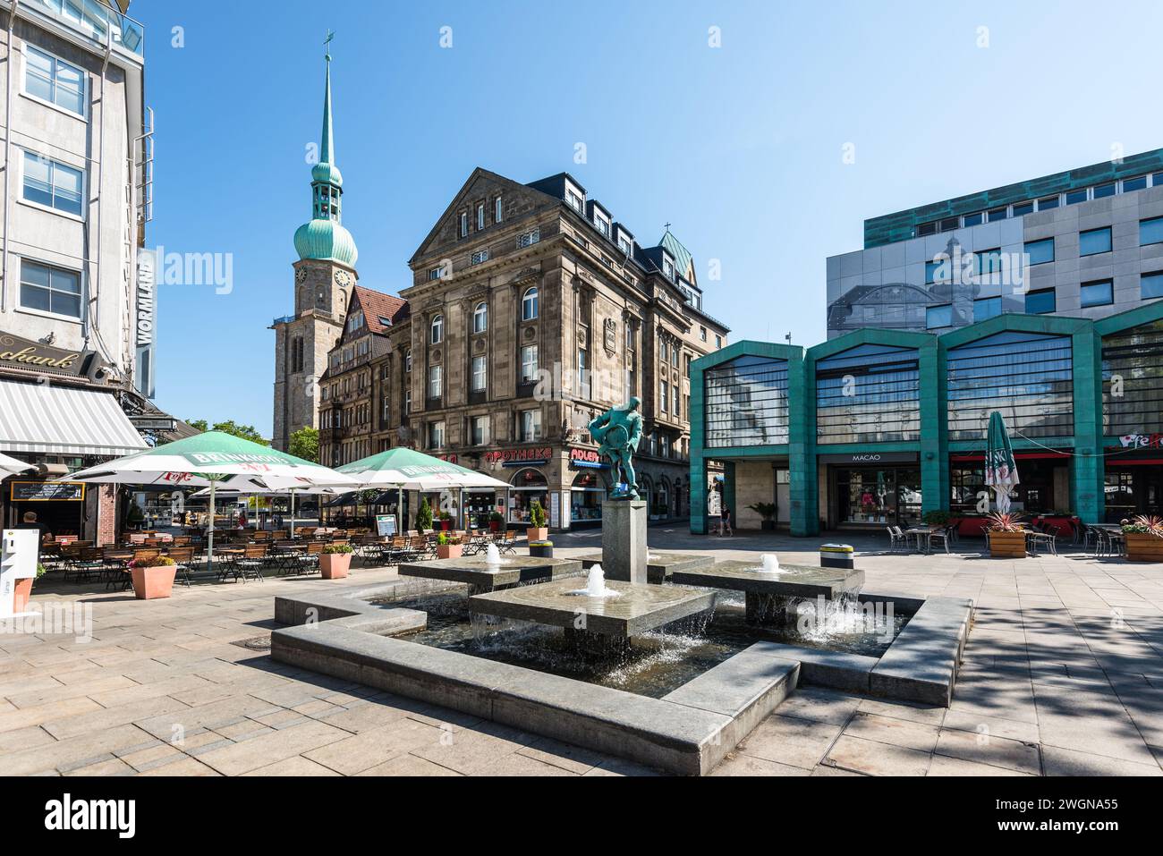 Dortmund, Germany - August 14, 2022: Blaeserbrunnen (horn blower fountain) on the old market with the Adler pharmacy and the church St. Reinoldi in th Stock Photo