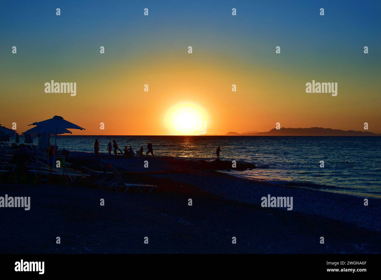 Silhouettes of people during sunset time at the beach of Ialyssos in the Greek Island of Rhodes Stock Photo