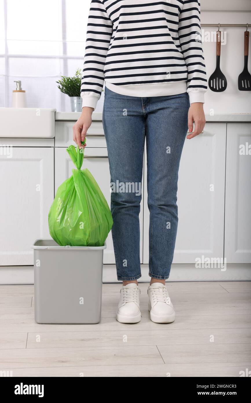Woman taking garbage bag out of trash bin in kitchen, closeup Stock Photo