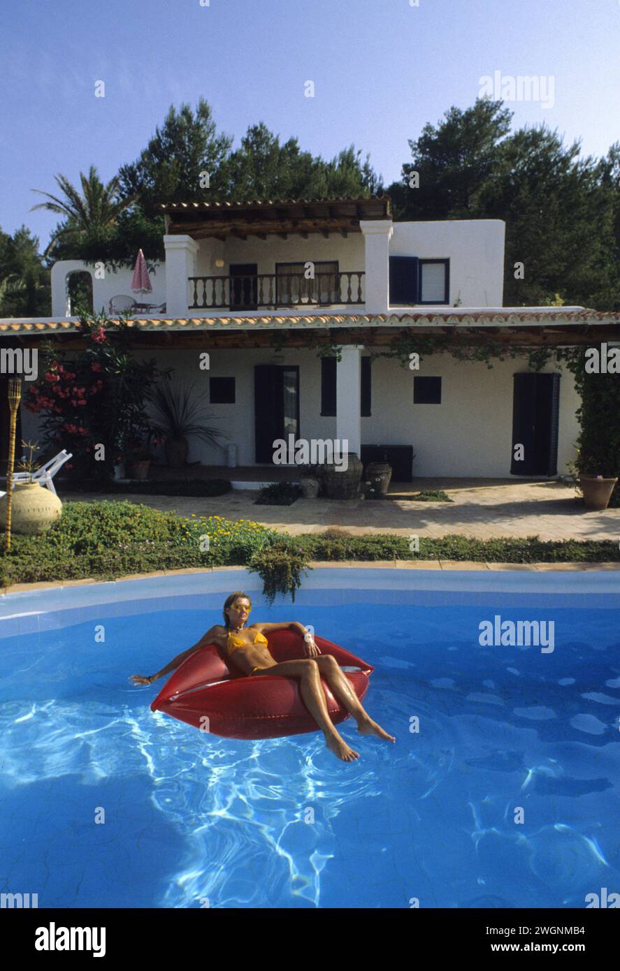pretty young blond hair woman lay down plastic mattress on swimming pool villa Stock Photo