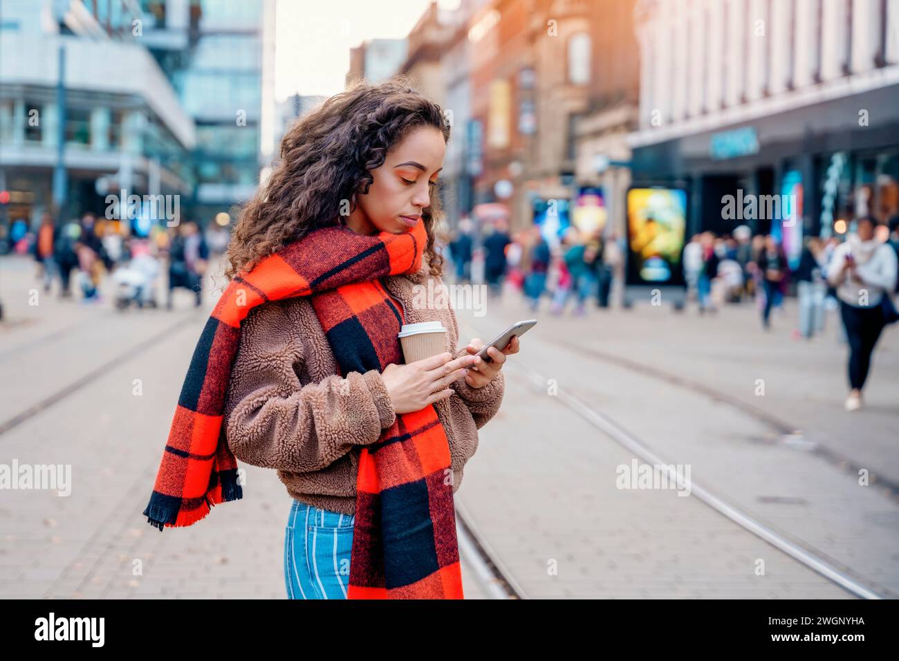 Outdoor portrait of upset  woman using a mobile phone and drinking coffee in Europe city Stock Photo