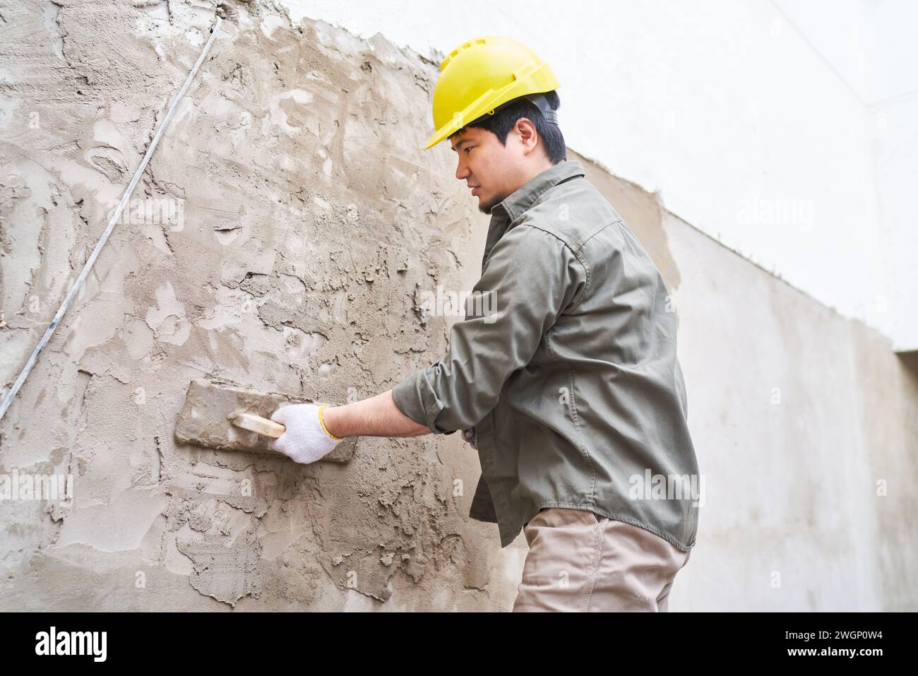 Male labor plastering on wall with mortar Stock Photo