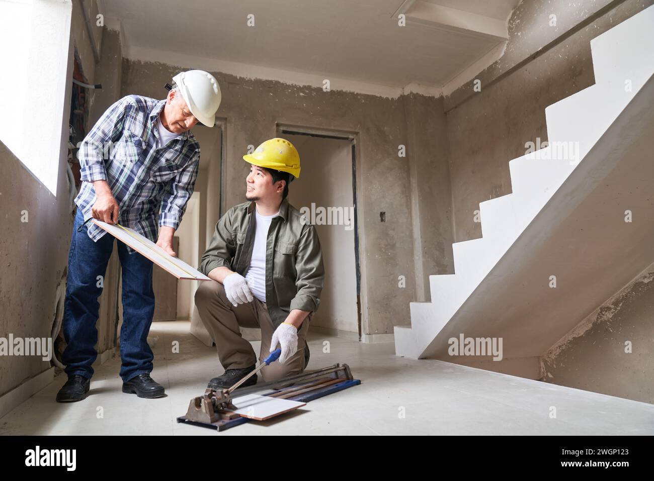 Contractor measuring plank and talking to worker Stock Photo
