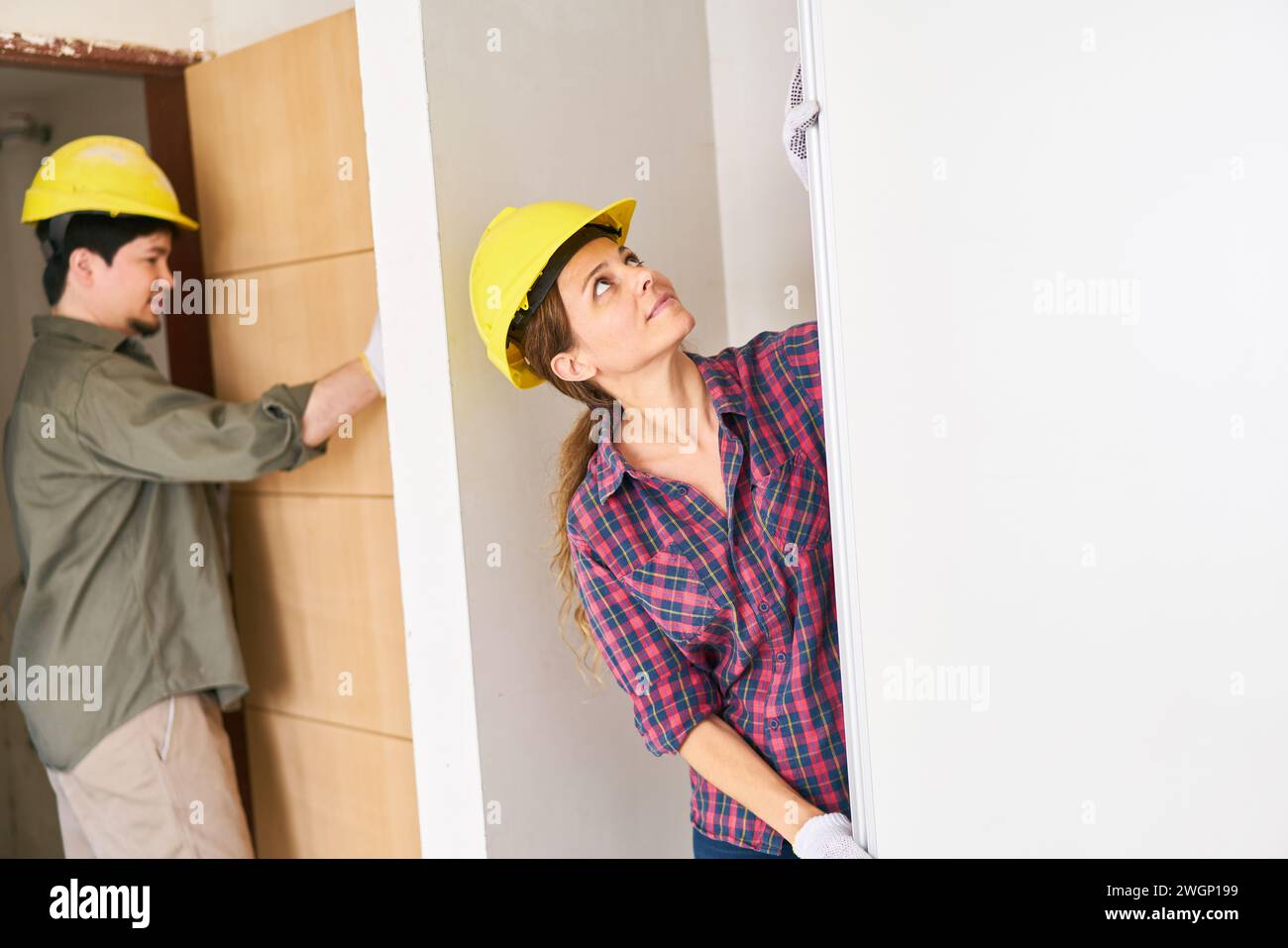 Young female worker fitting door Stock Photo