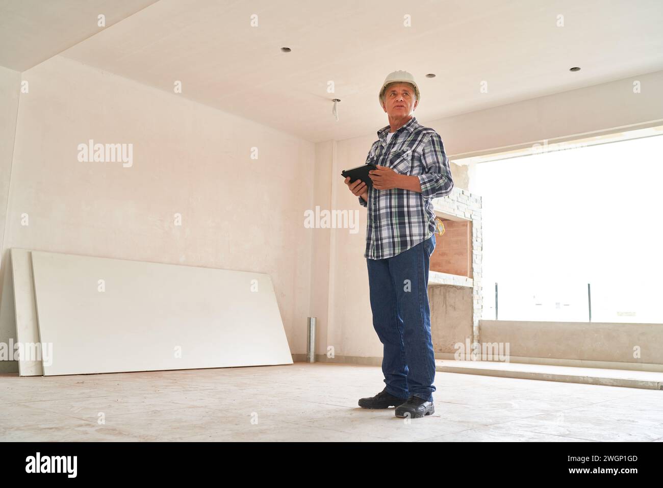 Architect wearing hardhat standing with tablet PC Stock Photo