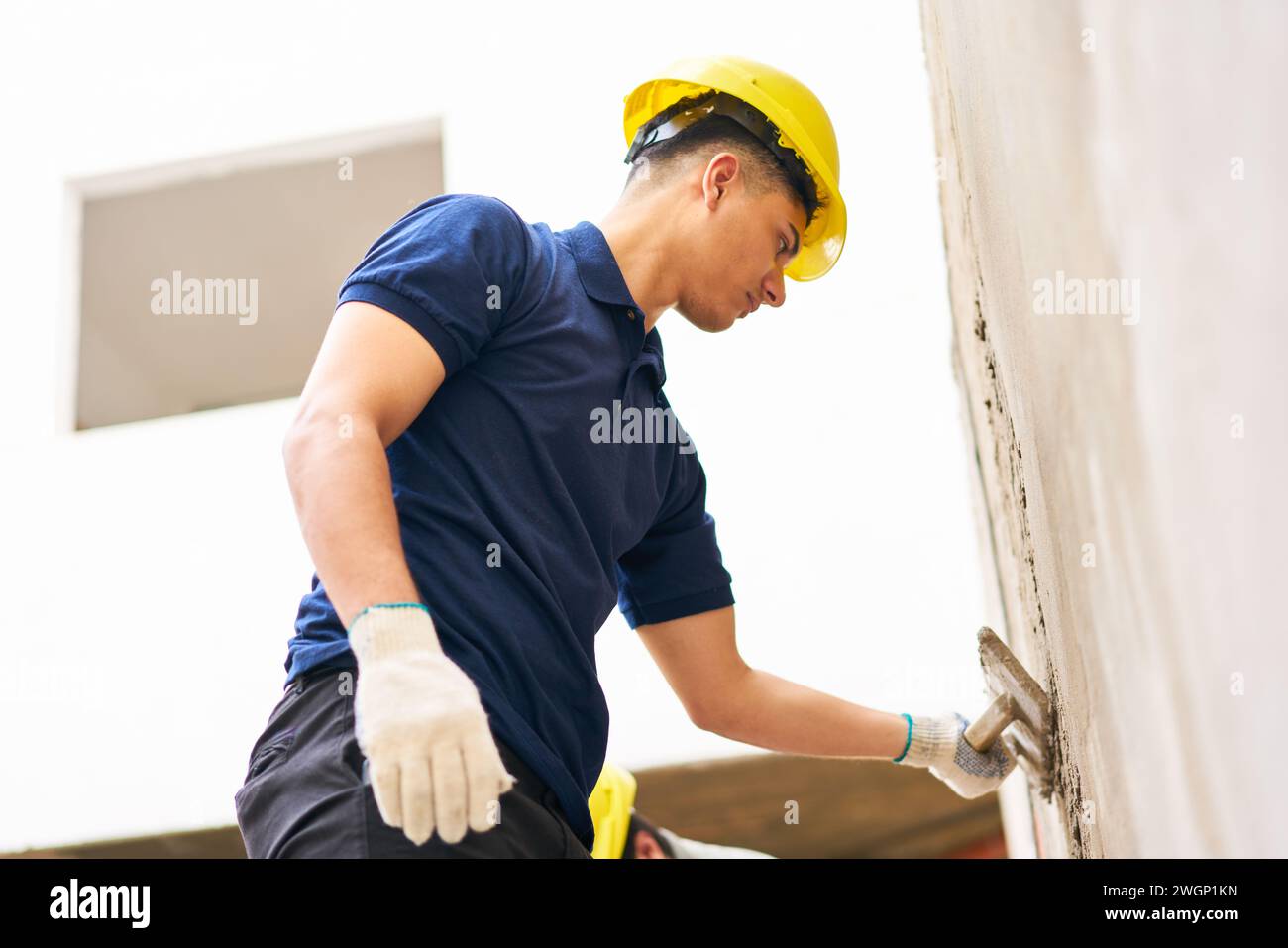 Male mason applying cement on wall Stock Photo