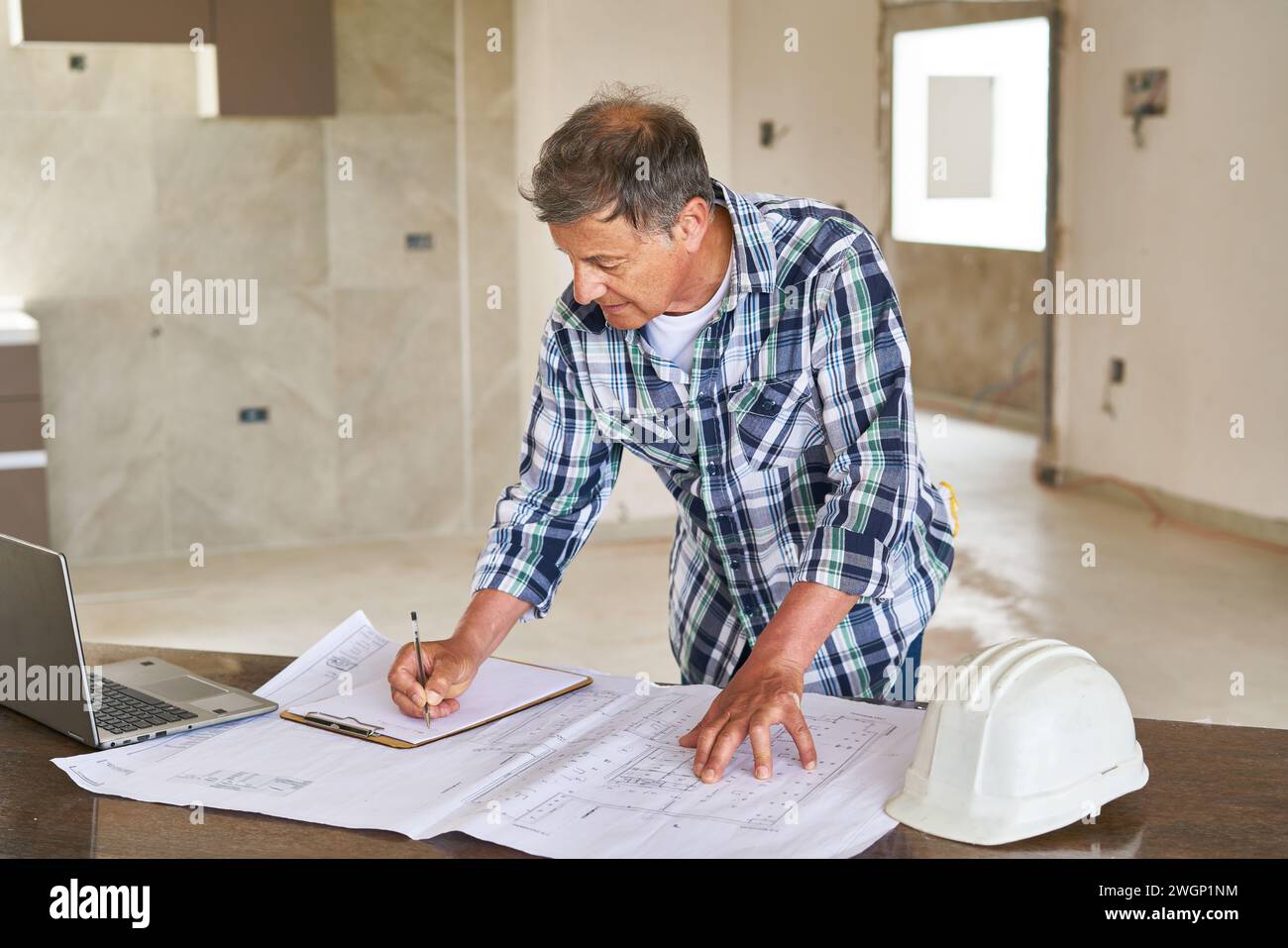 Senior architect writing on clipboard over design Stock Photo