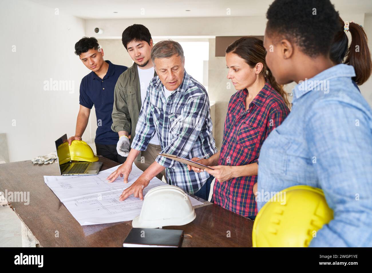 Senior architect discussing blueprint with coworkers Stock Photo