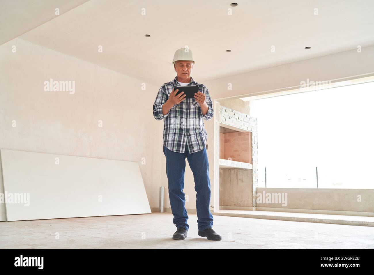 Contractor wearing hardhat standing with tablet PC Stock Photo