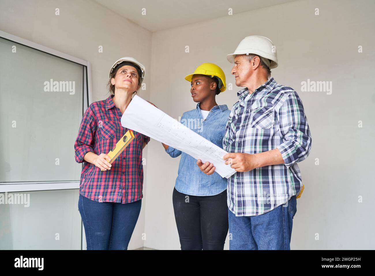 Workers discussing over blueprint with contractor Stock Photo