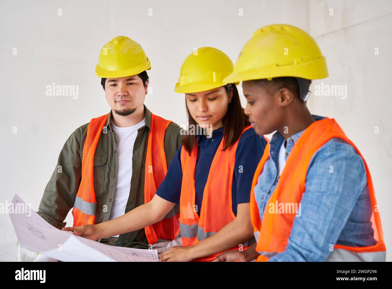 Diverse team discussing while examining blueprint Stock Photo