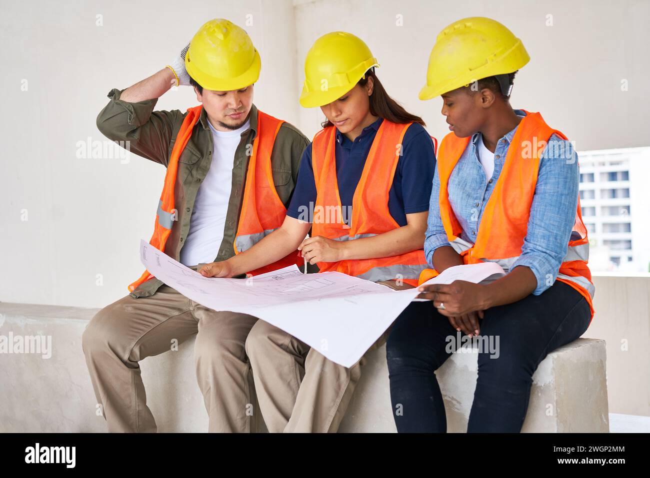 Diverse coworkers discussing while examining blueprint Stock Photo