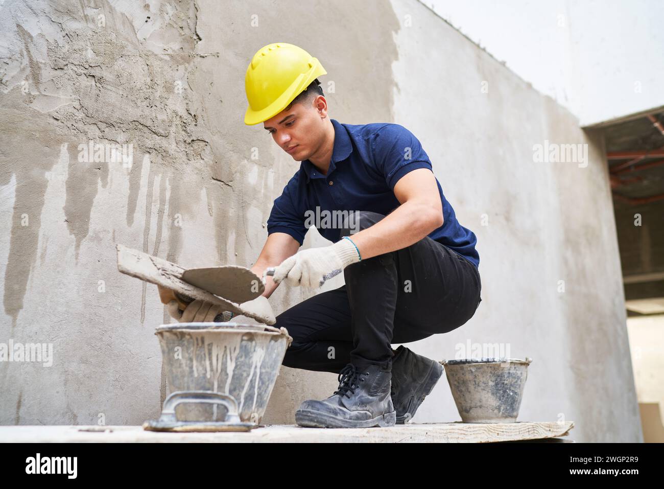 Male mason with trowel taking cement from bucket Stock Photo