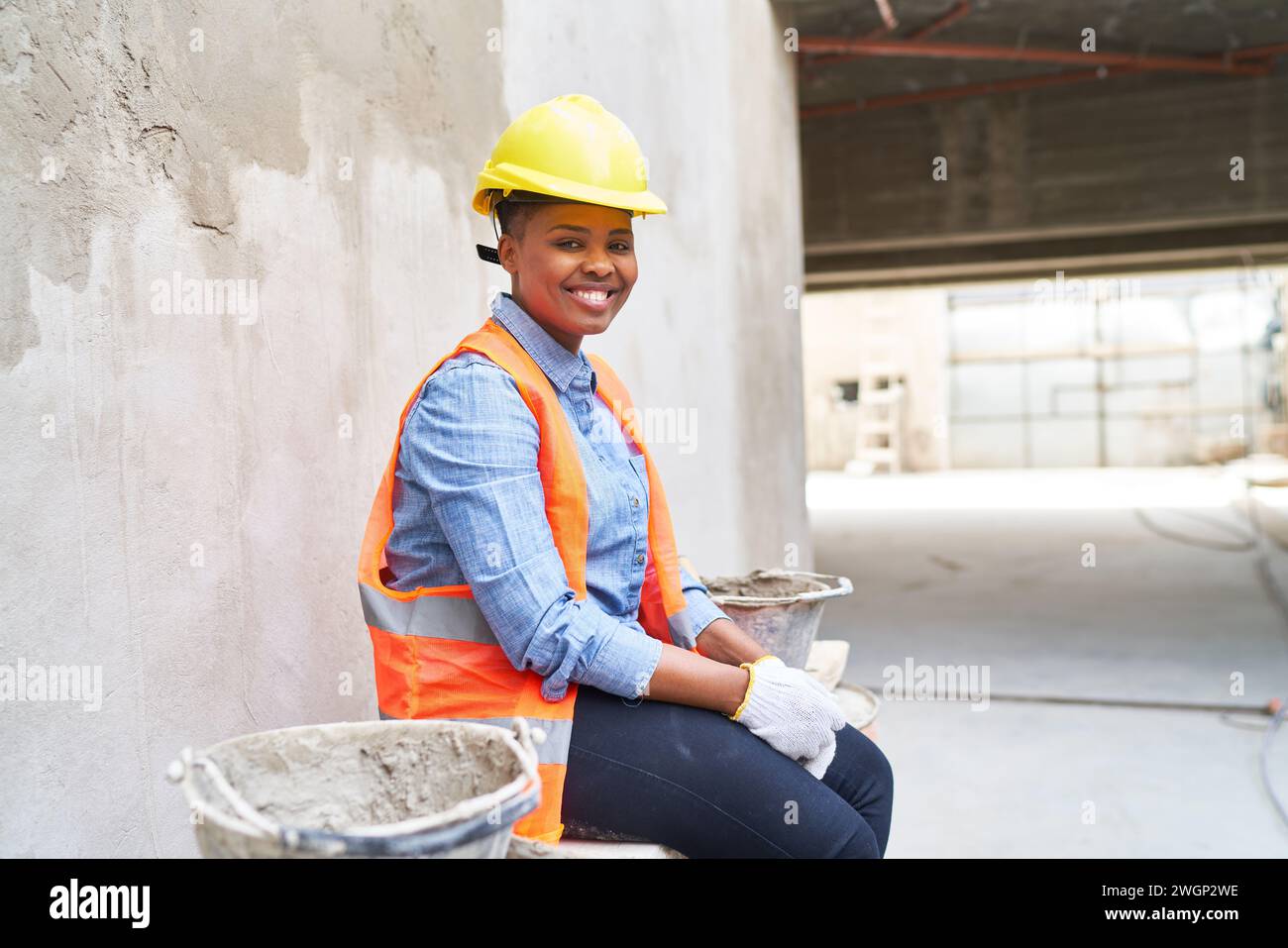 Smiling female bricklayer amidst buckets Stock Photo