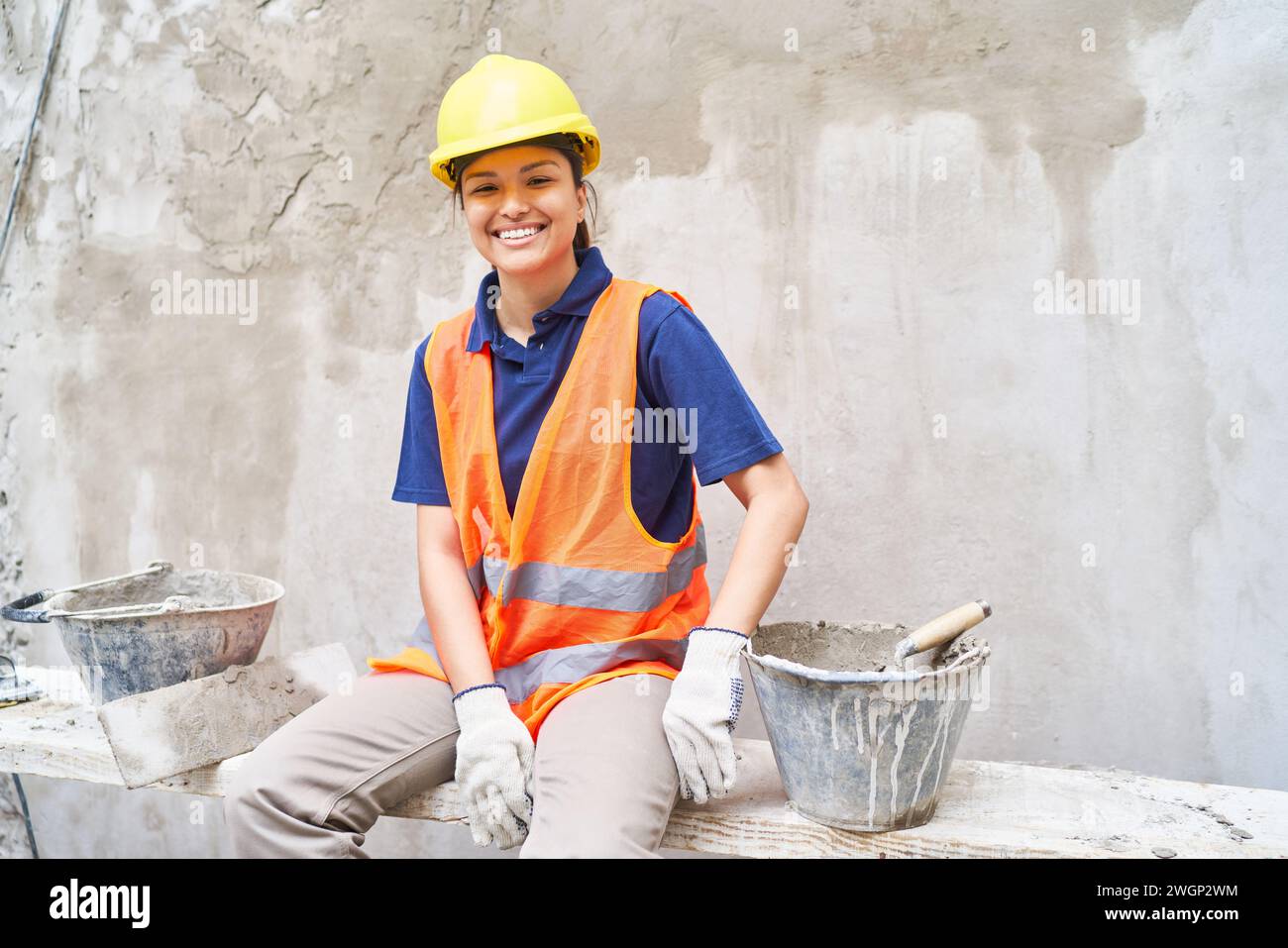 Happy female bricklayer amidst buckets Stock Photo