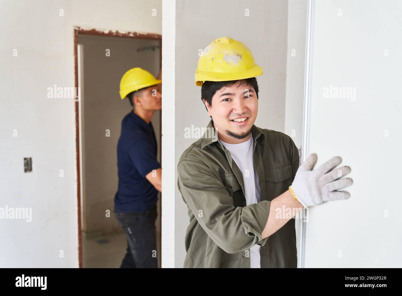 Smiling male worker fitting door Stock Photo