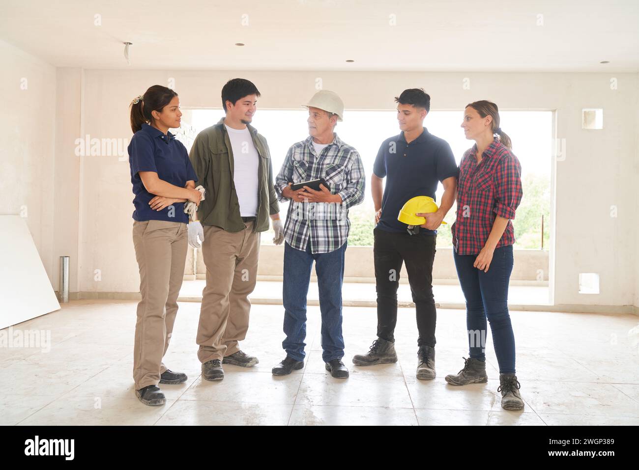 Contractor holding tablet PC discussing with team Stock Photo