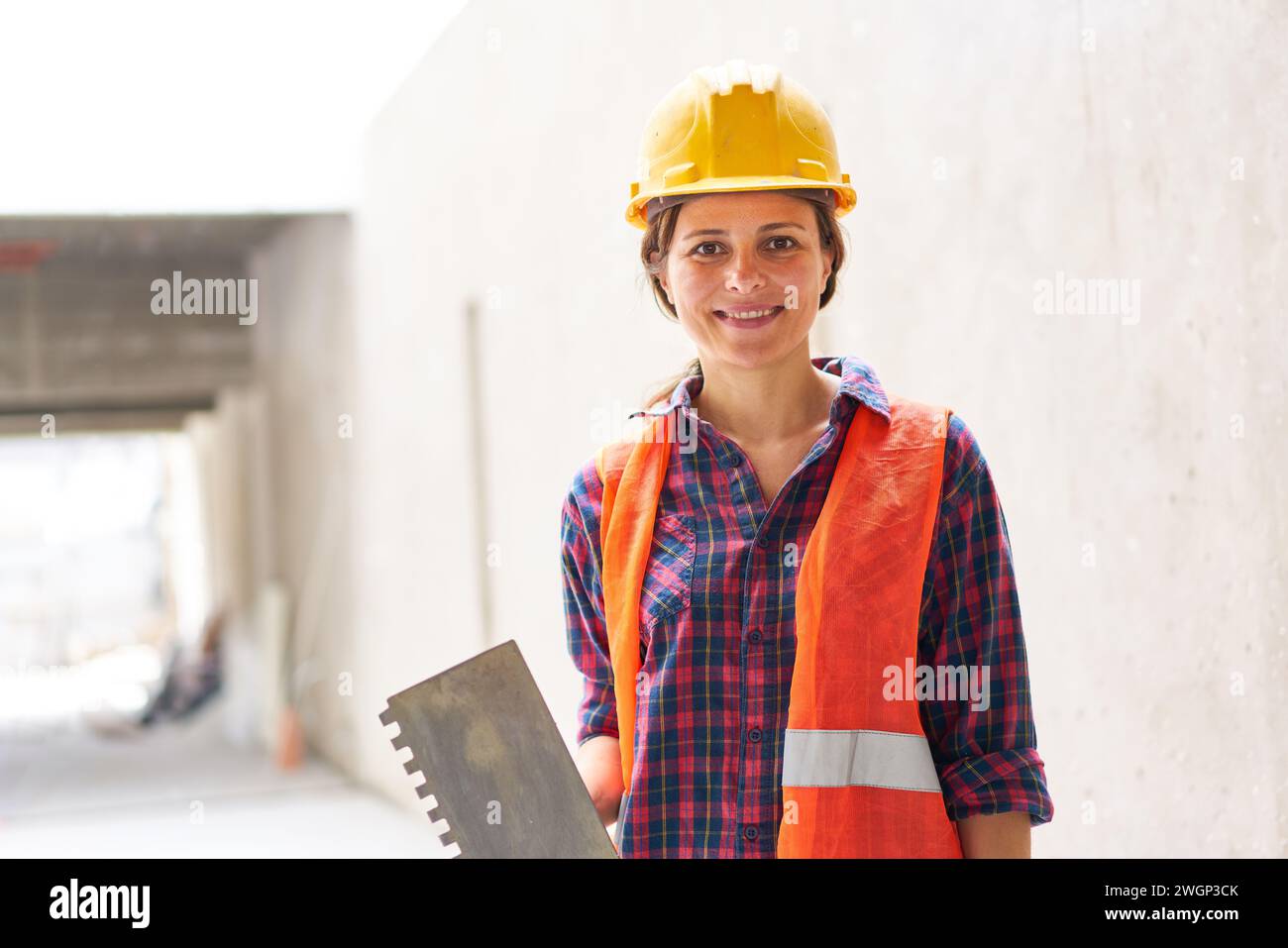 Confident female construction worker holding trowel Stock Photo