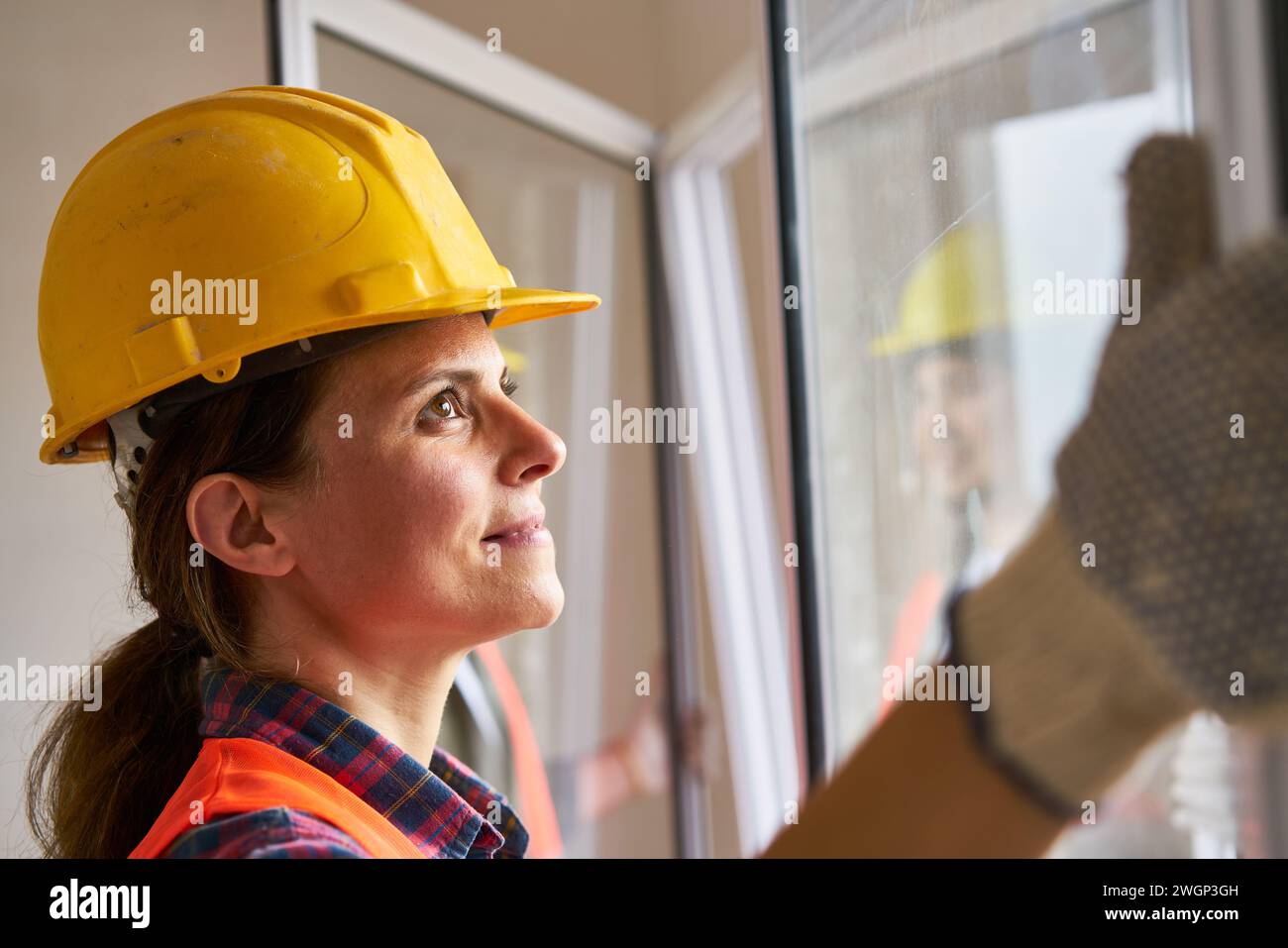 Female construction worker carrying window frame Stock Photo