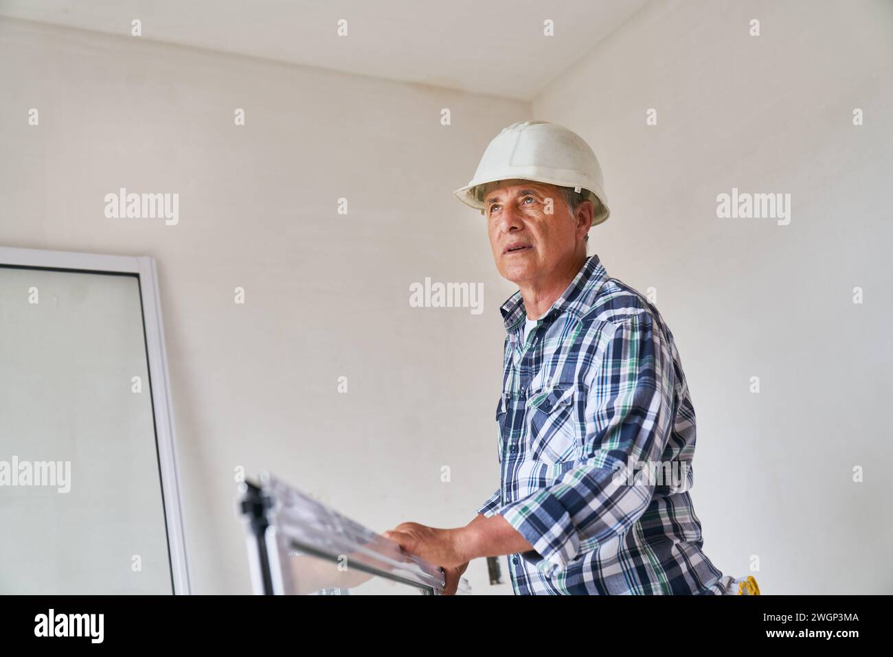 Senior male carpenter standing with window frame Stock Photo