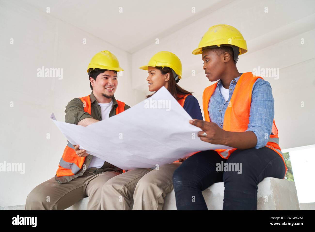 Diverse team discussing while examining blueprint Stock Photo