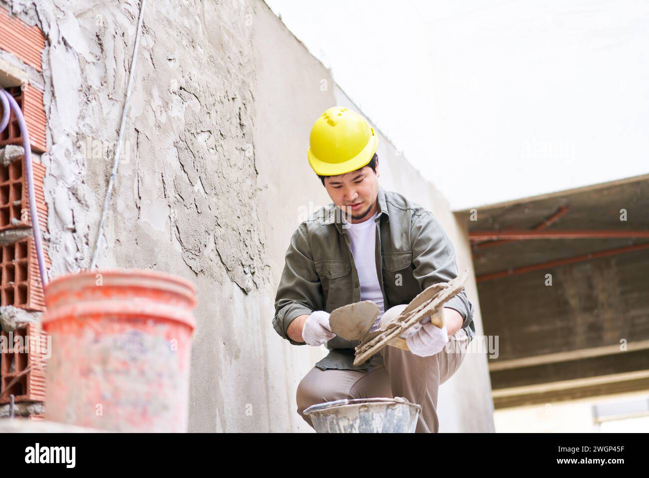 Skilled male worker taking cement from bucket Stock Photo