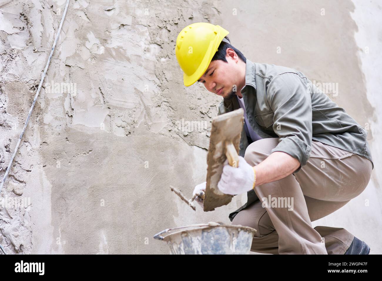 Skilled male mason taking cement from bucket Stock Photo