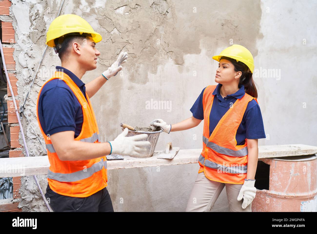 Confident mason coworkers discussing near wall Stock Photo