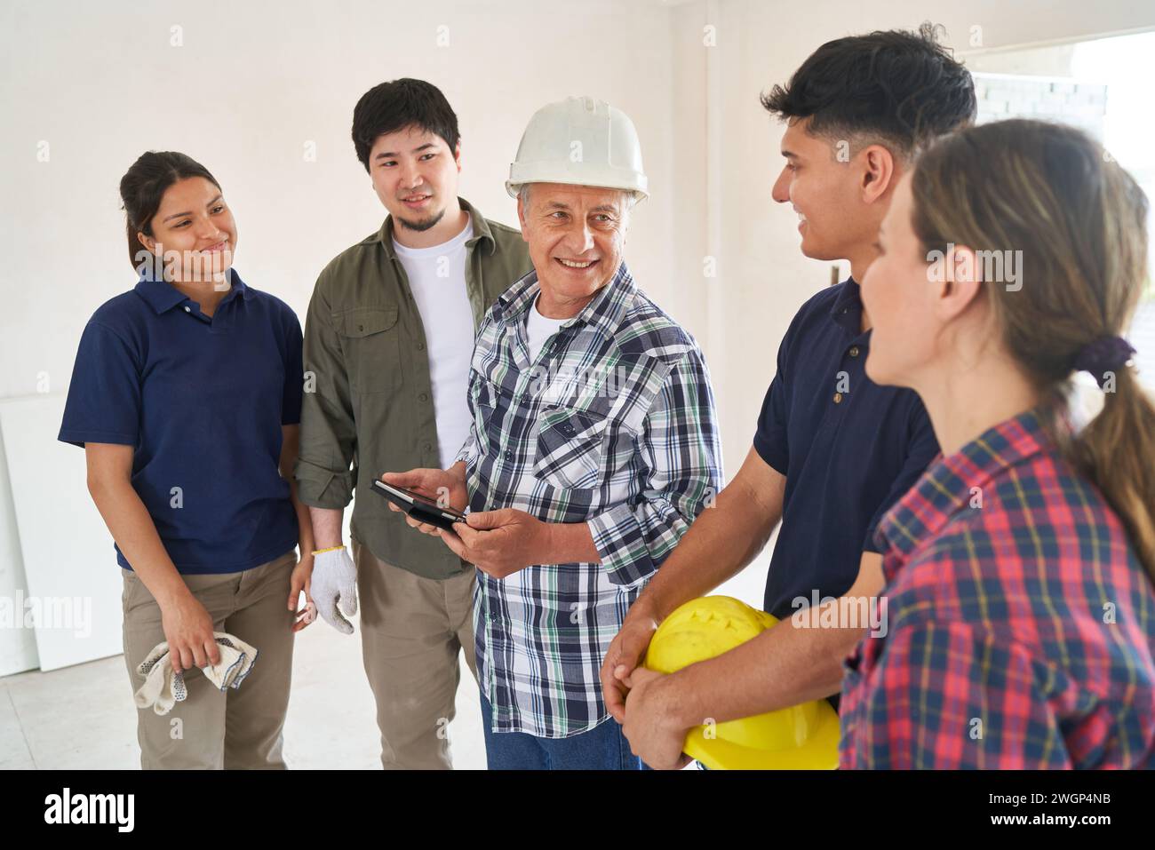 Senior contractor holding tablet PC discussing with team Stock Photo