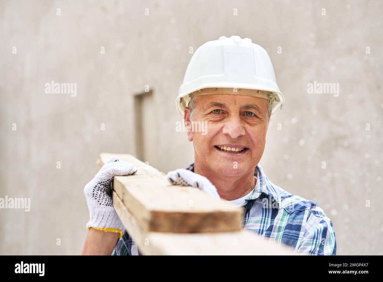 Senior male carpenter carrying planks on shoulder Stock Photo