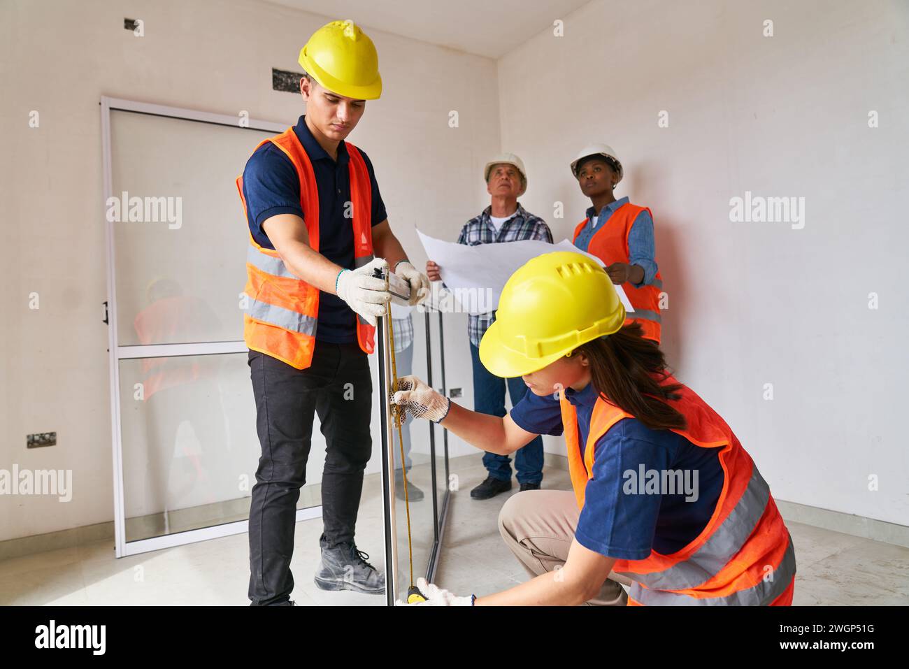 Carpenters examining window frame near coworkers Stock Photo