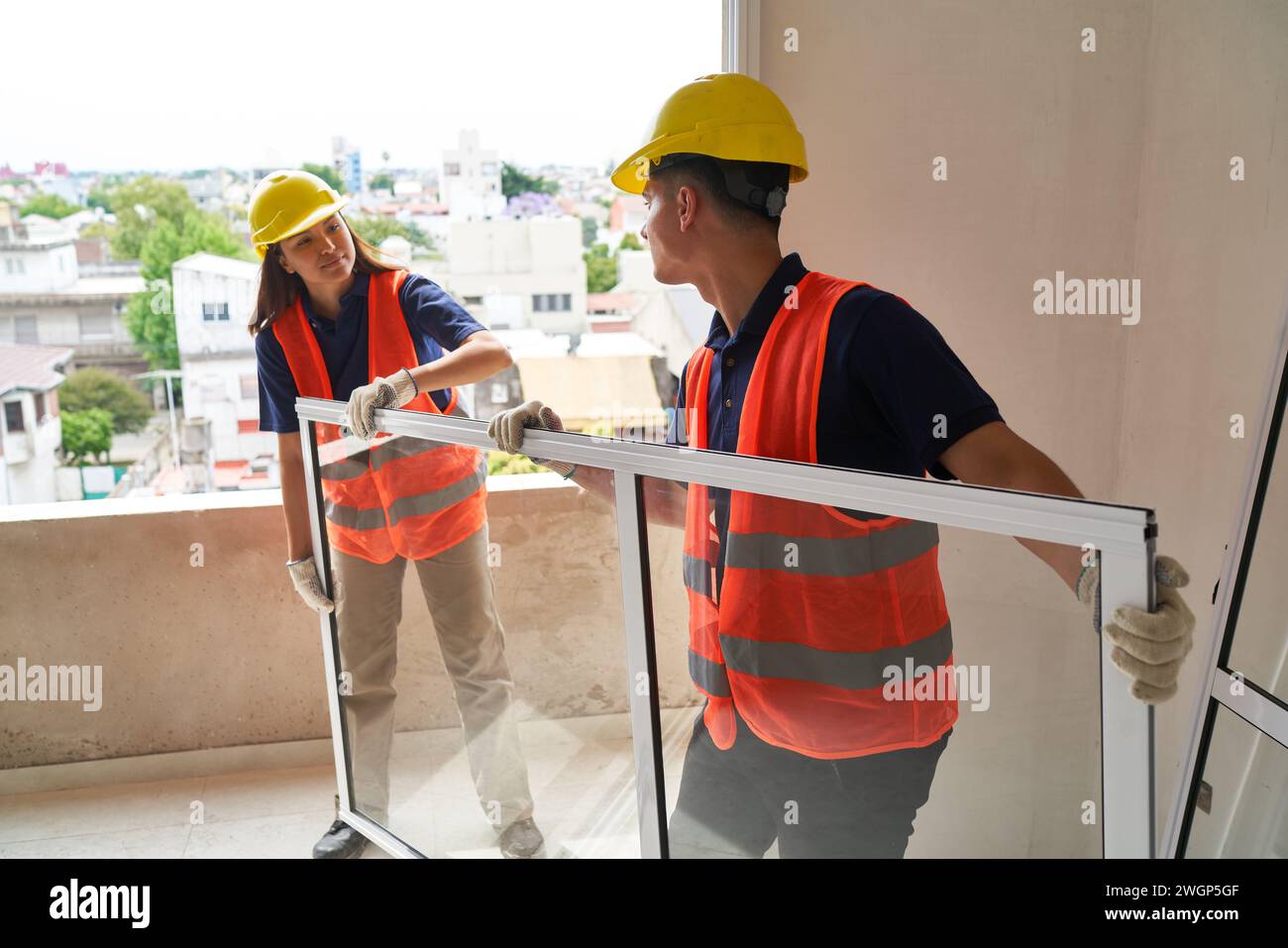 Young carpenters carrying window in incomplete house Stock Photo