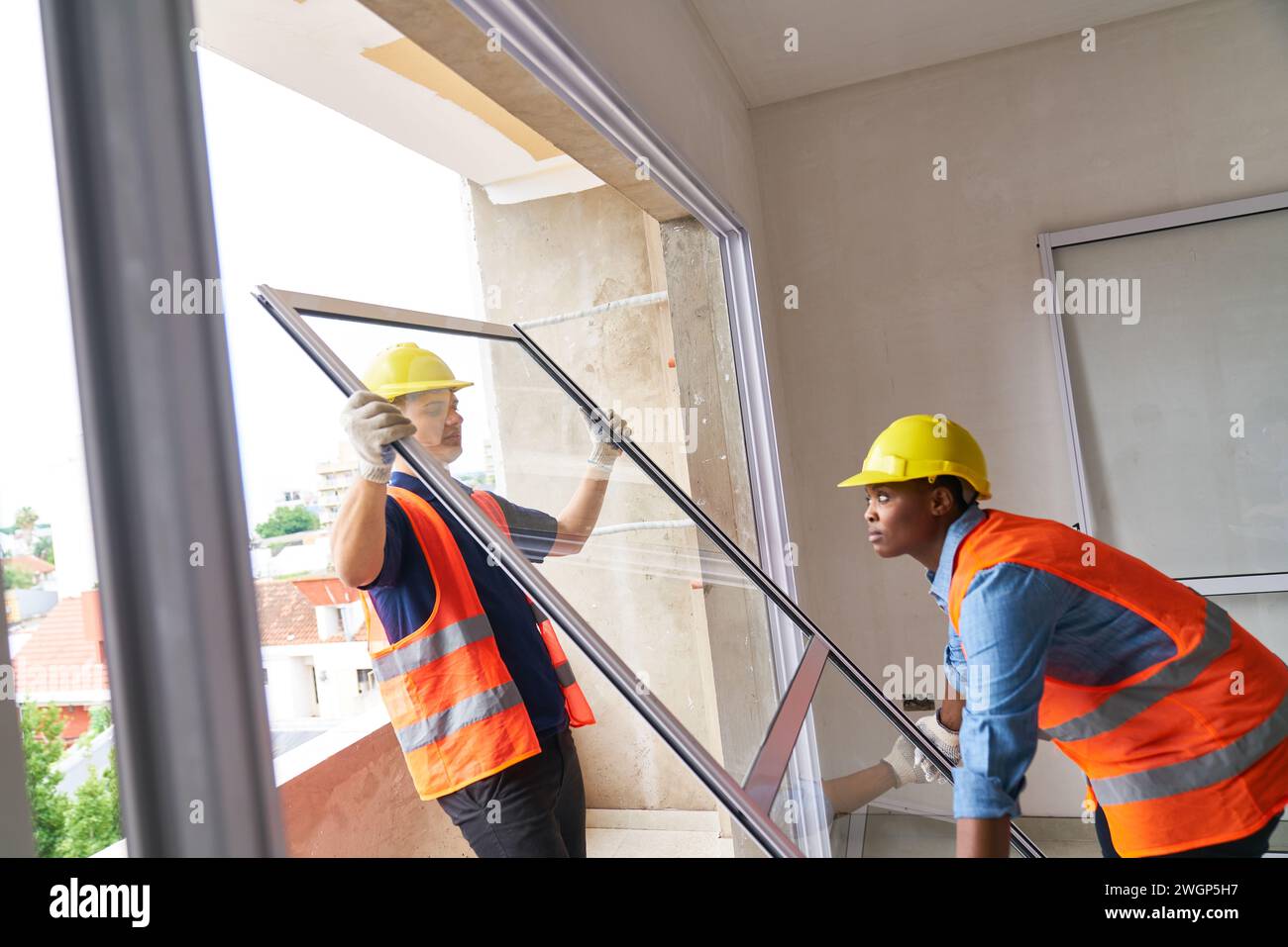 Young diverse carpenters carrying window in house Stock Photo