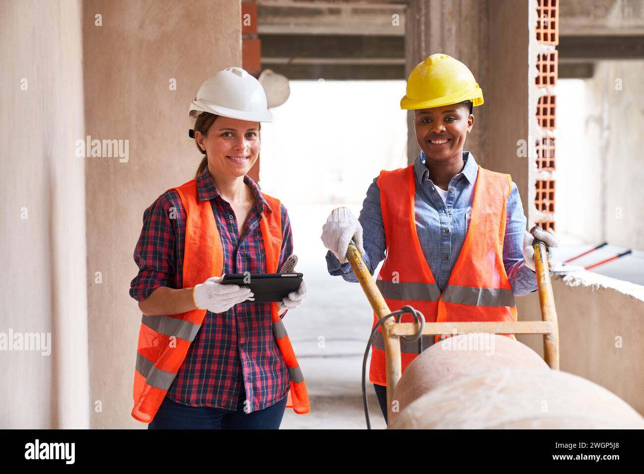 Smiling contractor with tablet PC standing by mason Stock Photo