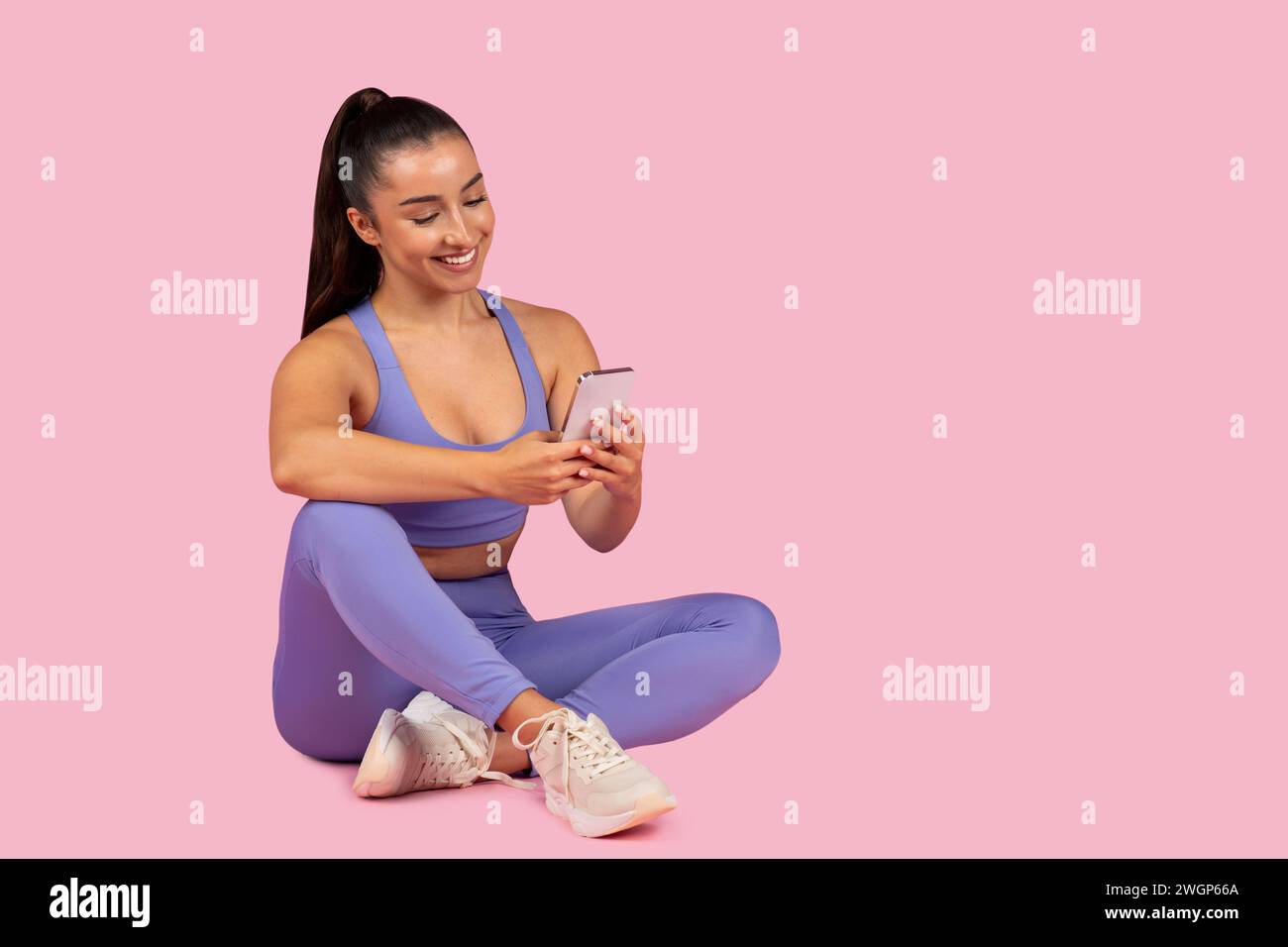 Young woman in activewear using phone post-workout Stock Photo