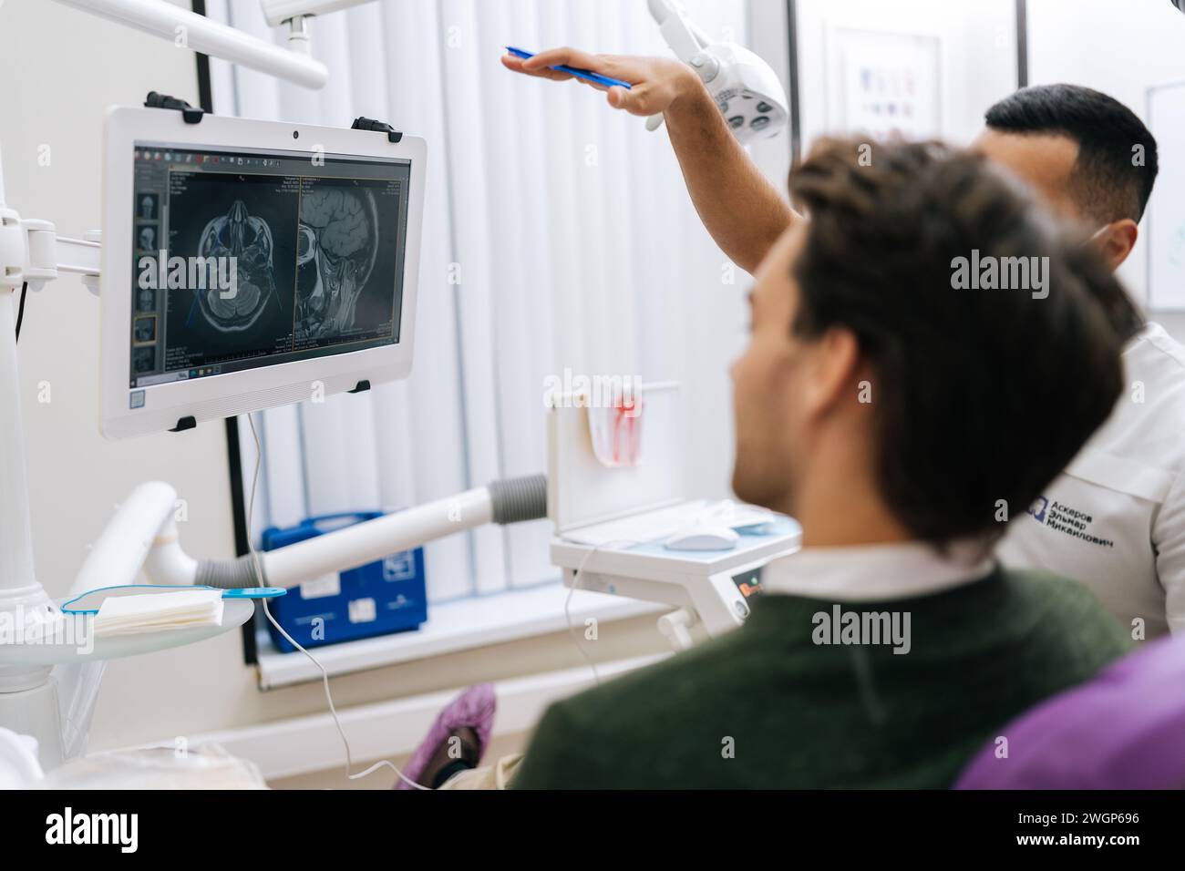 Male dentist showing at teeth radiography on monitor to explain dentition diagnosis to young man