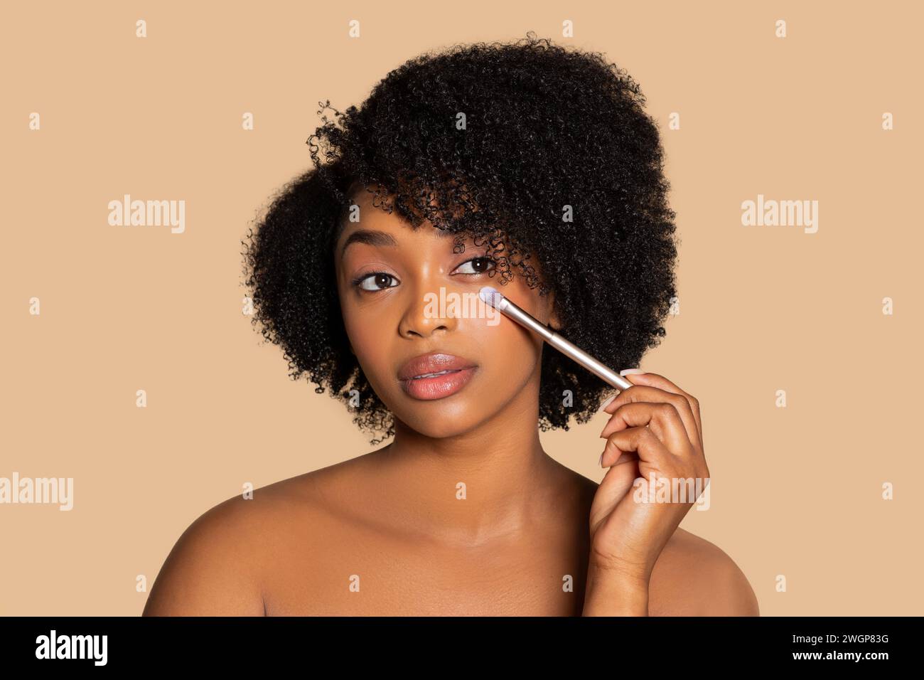 Woman applying eye makeup with brush, neutral tone Stock Photo